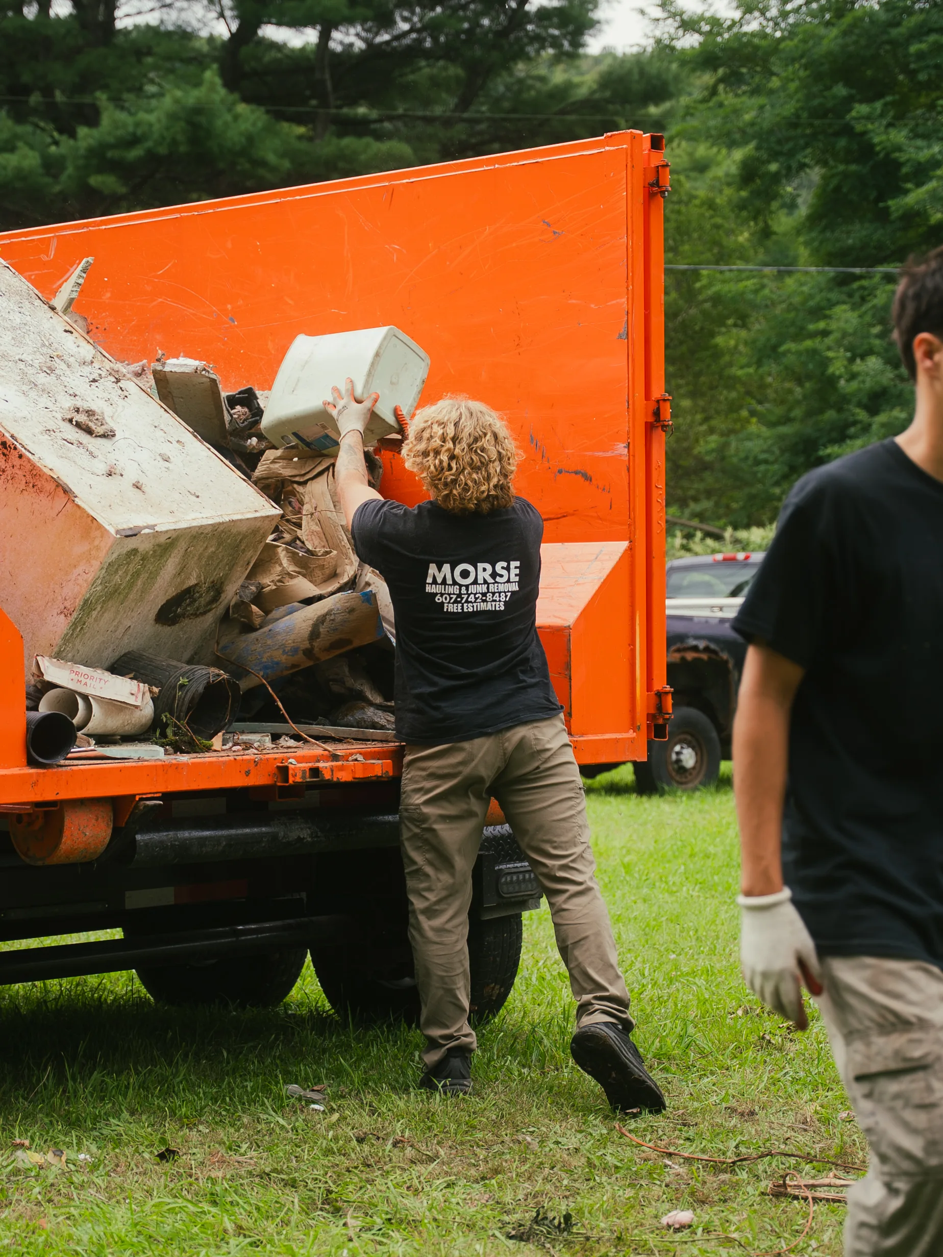 Morse Dumpsters crew loading debris into an orange roll-off dumpster in the Southern Tier